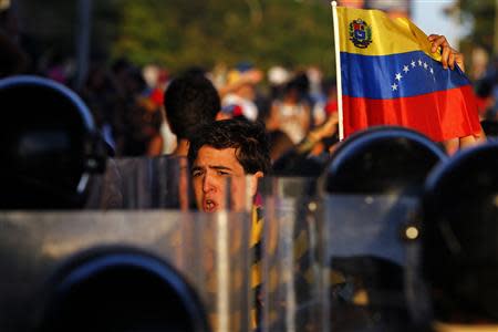 Opposition demonstrators stand in front of police as they block the city's main highway during a protest against Nicolas Maduro's government in Caracas February 14, 2014. REUTERS/Carlos Garcia Rawlins