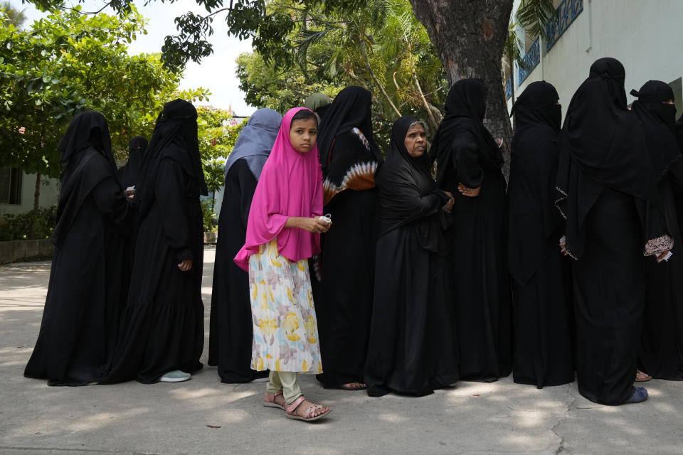 A girl stands with elders waiting to cast their votes at a polling station in Bengaluru, India, Wednesday, May 10, 2023. People in the southern Indian state of Karnataka were voting Wednesday in an election where pre-poll surveys showed the opposition Congress party favored over Prime Minister Narendra Modi's governing Hindu nationalist party. (AP Photo/Aijaz Rahi)