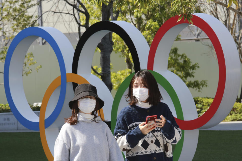 ARCHIVO - En esta foto de archivo del 17 de marzo de 2021, gente pasa frente a los anillos olímpicos en Tokio. (AP Foto/Koji Sasahara)