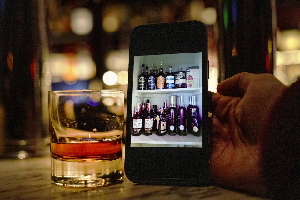 Cody Walding from Houston, Texas, shows a picture of his personal bourbon collection while tasting a bourbon at the Seven Grand bar, a whiskey bar downtown Los Angeles Tuesday, Feb. 28, 2023. Seven Grand offers an extensive selection of over 700 different whiskies from around the world, including rare and hard-to-find bottles. (AP Photo/Damian Dovarganes)