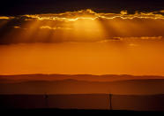 Wind turbines stand on a hill as sun rays fall through the clouds near Frankfurt, Germany, Tuesday, Aug. 25, 2020. (AP Photo/Michael Probst)