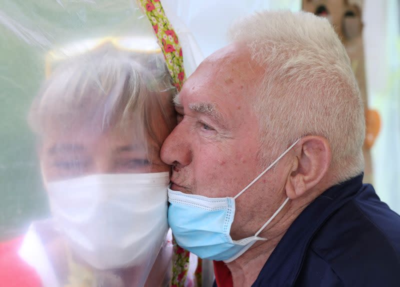 Residents at Belgian nursing home "Le Jardin de Picardie" enjoy hugs and cuddle through a wall made with plastic sheets to protect against potential COVID-19 infection in Peruwelz