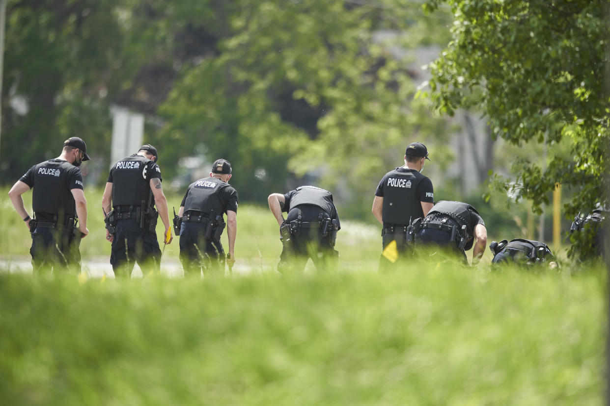 A line of police officers look for evidence at the scene of a car crash in London, Ontario on Monday, June 7, 2021. Police say multiple people have died after several pedestrians were struck by a car Sunday night. (Geoff Robins/The Canadian Press via AP)