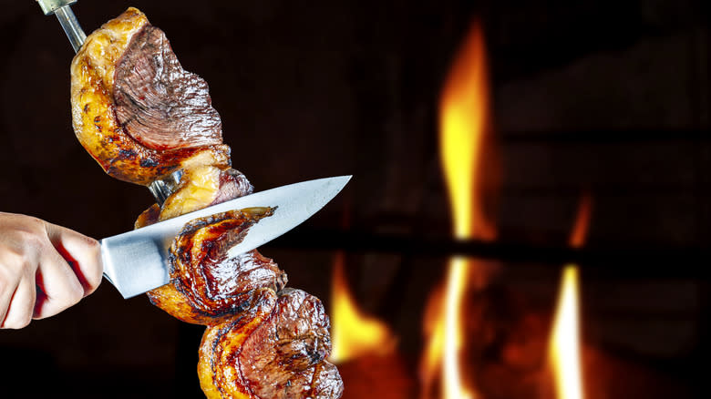 slicing steak with fire in the background