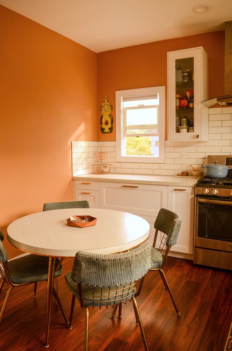 View of round dining table in orange kitchen.