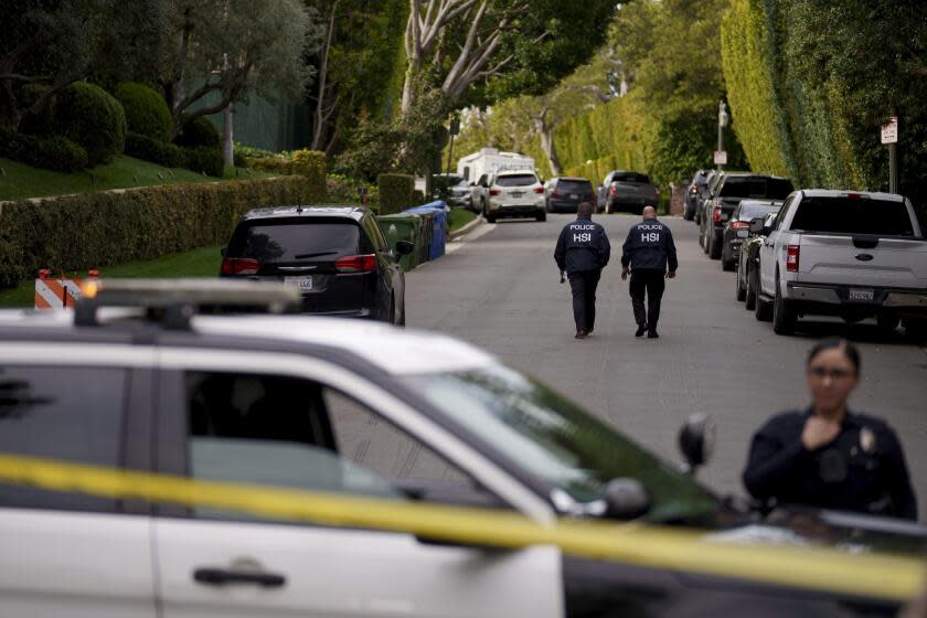 Authorities walk on a street near a property belonging to Sean "Diddy" Combs' on Monday, March 25, 2024, in Los Angeles, after federal law enforcement executed a raid as part of an ongoing sex trafficking investigation by federal authorities in New York. (AP Photo/Eric Thayer)