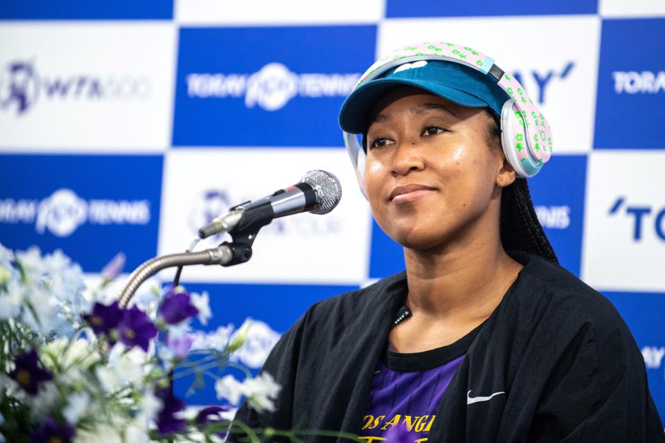 A close-up of Naomi at a microphone and wearing headphones