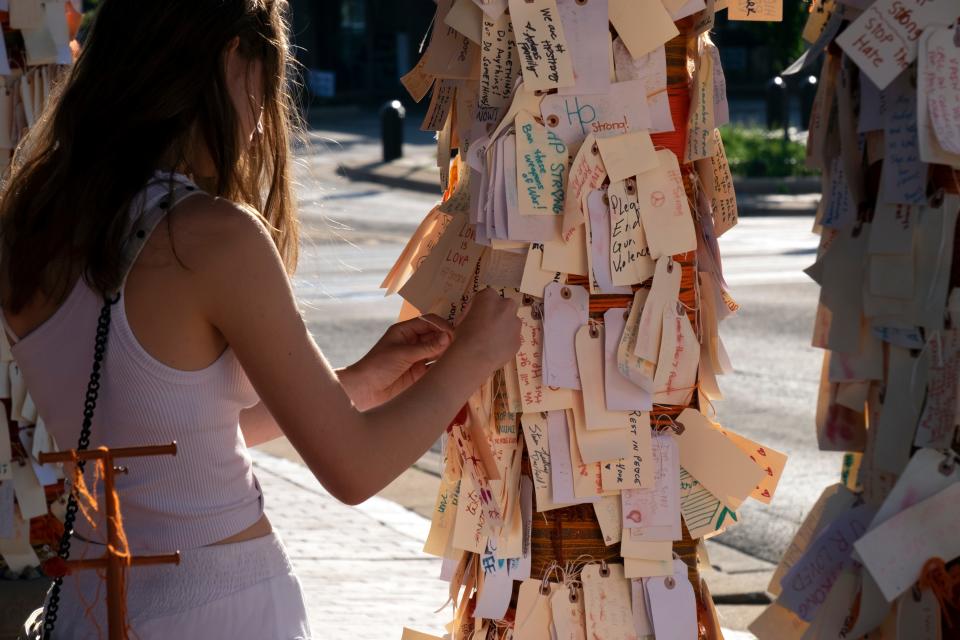 A girl places a note on a memorial for the victims of the mass shooting at a Fourth of July parade in downtown Highland Park, Illinois, on Aug. 2, 2022.