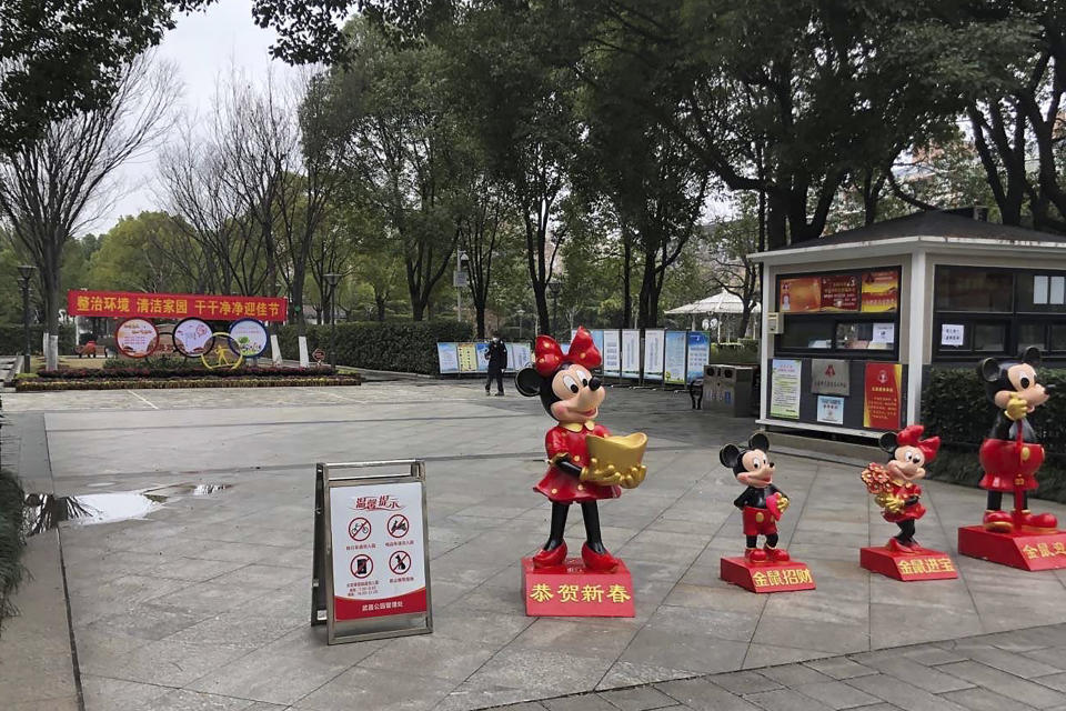 In this photo provided to the Associated Press, a man wearing a face mask walks past Minnie and Mickey Mouse themed Lunar New Year decorations at a park in Wuhan in central China's Hubei Province, Monday, Jan. 27, 2020. China on Monday expanded sweeping efforts to contain a viral disease by extending the Lunar New Year holiday to keep the public at home and avoid spreading infection. (AP Photo)