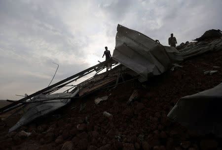 Palestinians survey the scene of an Israeli airstrike at a Hamas outpost in the central Gaza Strip October 9, 2017. REUTERS/Ibraheem Abu Mustafa