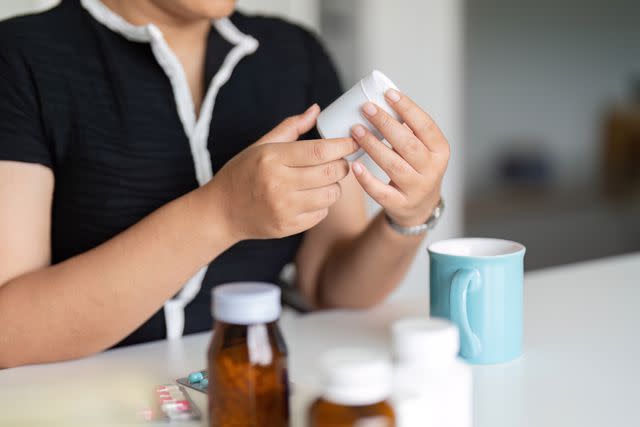 <p>Natee Meepian / Getty Images</p> Female reading pharmacy label