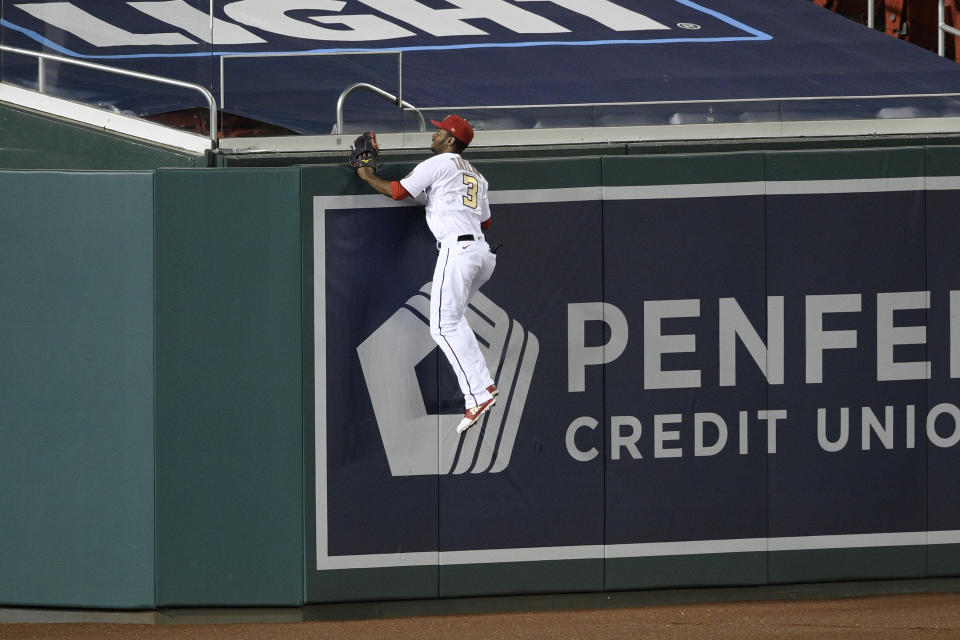 Washington Nationals center fielder Michael A. Taylor climbs the wall in vain on a home run by Philadelphia Phillies' Bryce Harper during the sixth inning of a baseball game Wednesday, Sept. 23, 2020, in Washington. (AP Photo/Nick Wass)