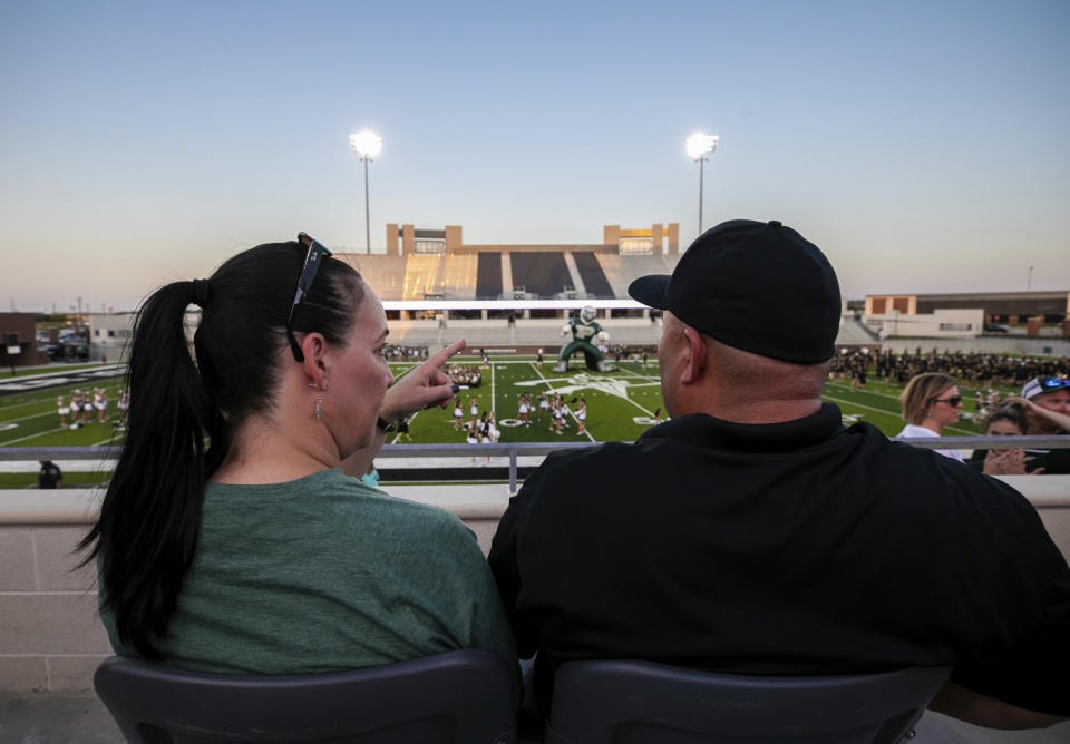 Lisa DeMarco and Rey Martinez watch students on the field during the opening of the new Children's Health Stadium at Prosper ISD on Saturday, Aug. 17, 2019, in Prosper, Texas. Democrats are out to show they’re serious about flipping Texas in 2020 by holding Thursday’s presidential debate in Houston. Republicans are coming off their worst election in Texas in a generation. Fast-changing suburbs are trending more liberal, and Democrats are counting on more left-leaning voters moving in to turn the state blue. But that transformation may not arrive by 2020, and the GOP is closely watching conservative bastions like the booming Dallas suburbs. (AP Photo/Nathan Hunsinger)