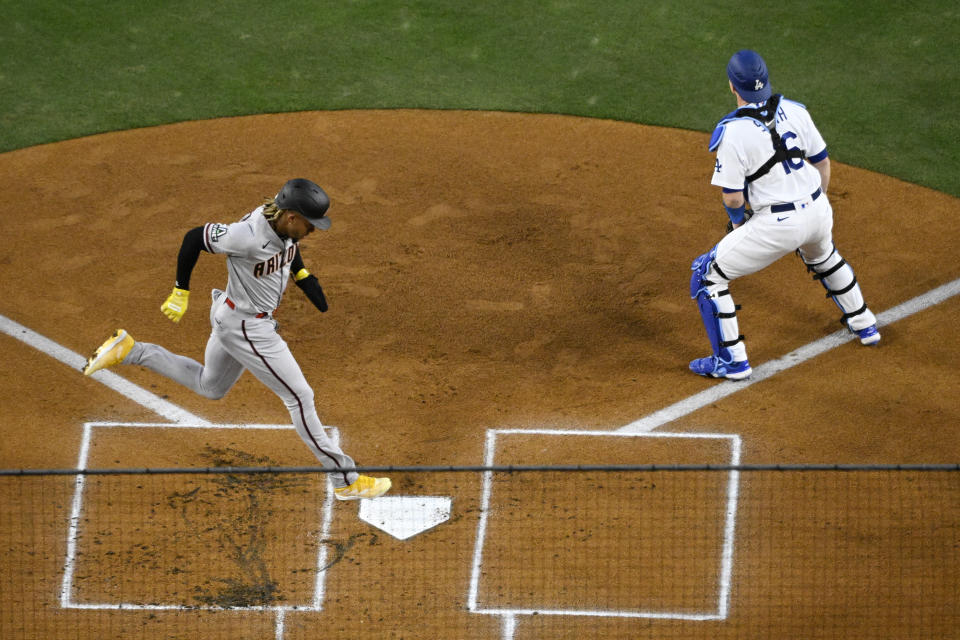 Arizona Diamondbacks' Ketel Marte, left, scores on a single by Christian Walker as Los Angeles Dodgers catcher Will Smith stands at the plate during the first inning of an opening day baseball game Thursday, March 30, 2023, in Los Angeles. (AP Photo/Mark J. Terrill)