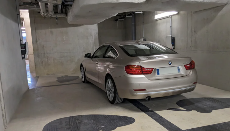 A BMW car parked in a basement garage with concrete walls