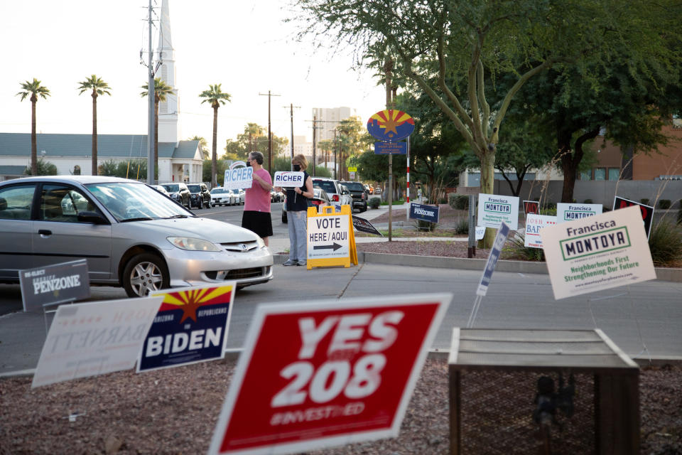 Arnie and Mary Richer wave to voters at Burton Barr Central Library on Nov. 3 in Phoenix, Arizona. (Photo by Courtney Pedroza/Getty Images)