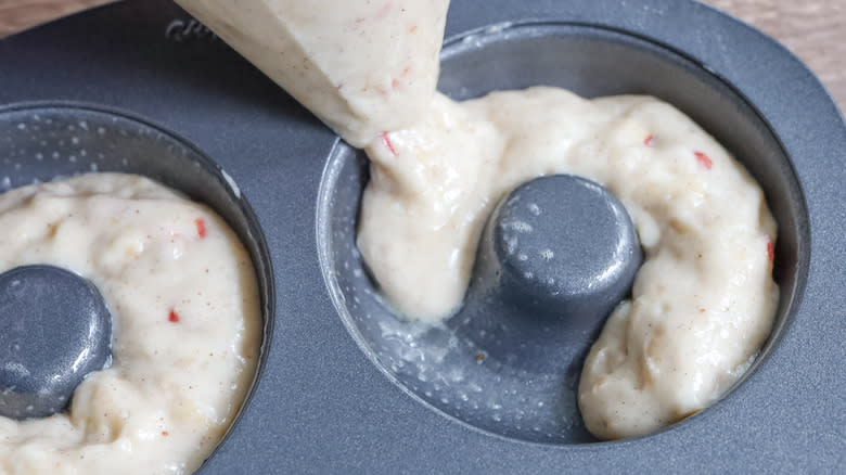 piping donut batter into pan