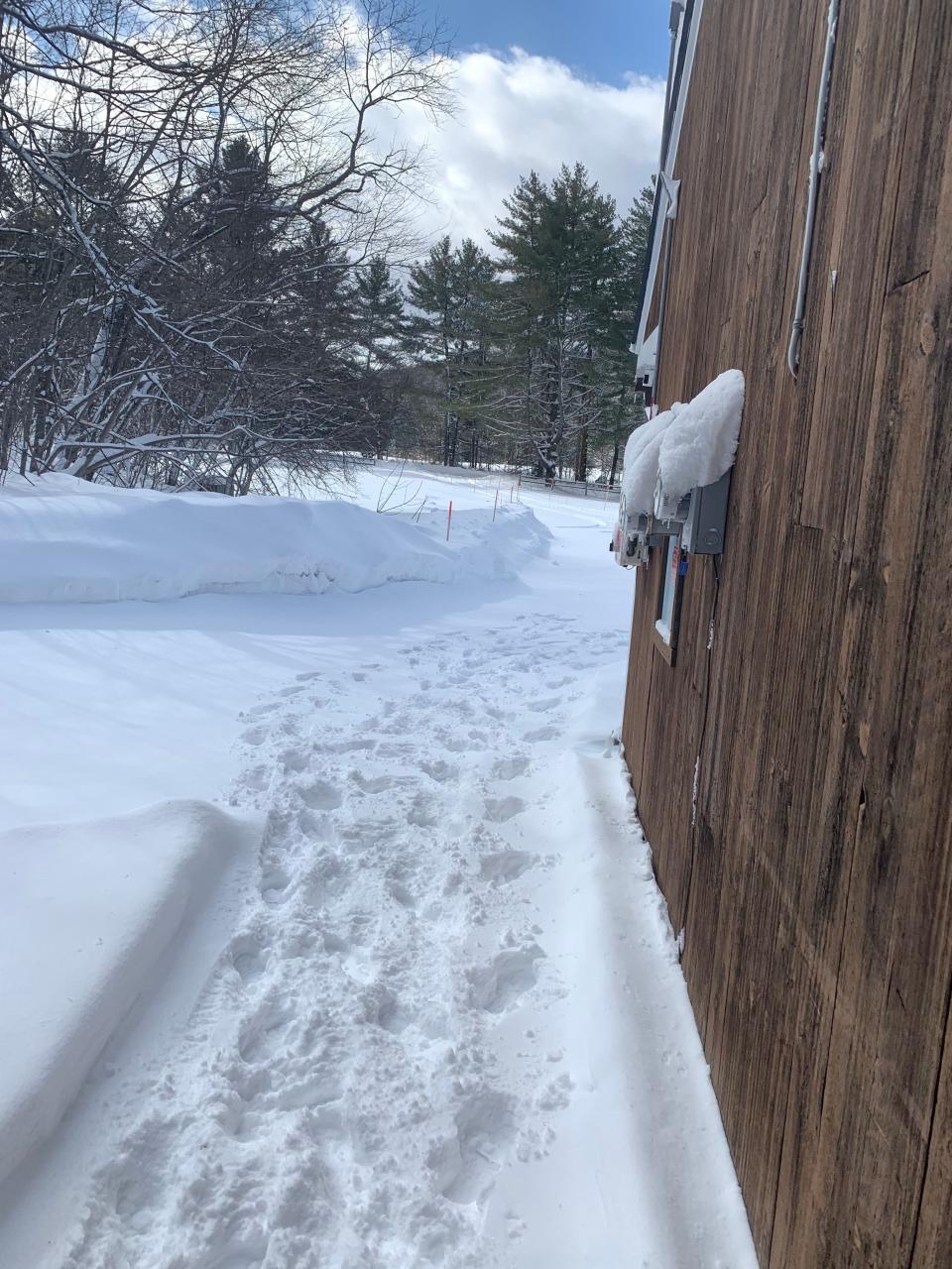 snowy exterior of matthew wilson's airbnb in vermont, snow trail on the left with apartment on the right