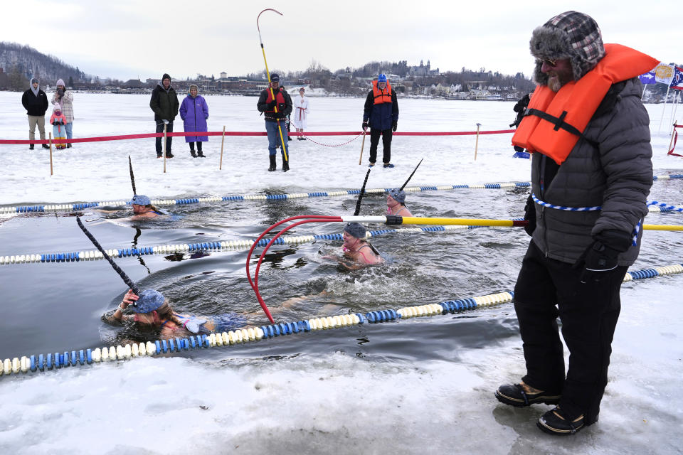 Swimmers dressed as narwals take a lap during the 25 meter hat competition during the winter swimming festival on frozen Lake Memphremagog, Friday, Feb. 23, 2024, in Newport, Vermont. (AP Photo/Charles Krupa)