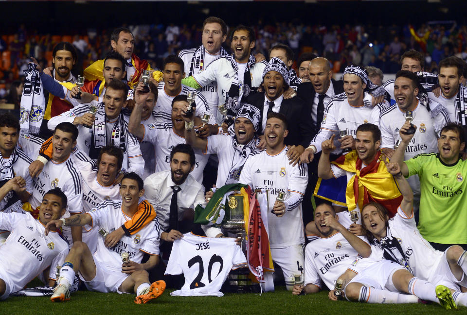 Real Madrid players celebrate with the trophy at the end of the final of the Copa del Rey between FC Barcelona and Real Madrid at the Mestalla stadium in Valencia, Spain, Wednesday, April 16, 2014. Real defeated Barcelona 2-1. (AP Photo/Manu Fernandez)