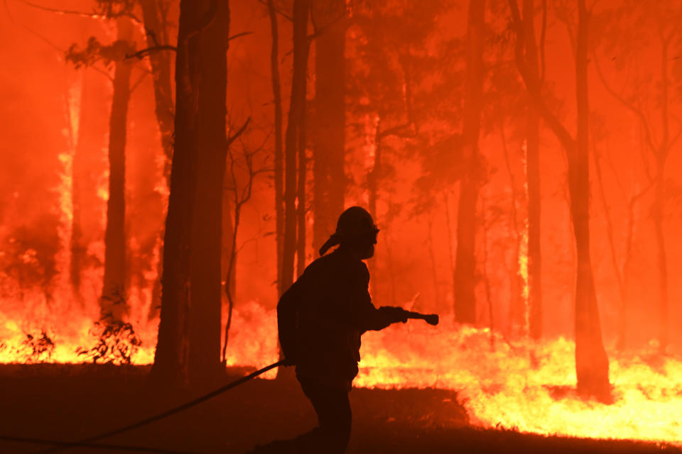 RFS volunteers and NSW Fire and Rescue officers protect a home southwest of Sydney on Tuesday. Source: AAP