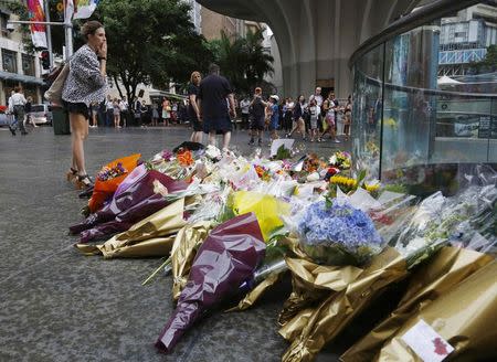 A woman blows a kiss after giving a floral tribute for those who died in the Sydney cafe siege, near the site of the incident, in Martin Place December 16, 2014. REUTERS/Jason Reed