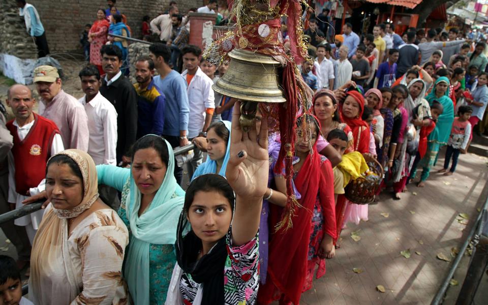 An Indian Hindu devotee rings the bell as a ritual as she stands with other devotees in a queue to pray - Credit: EPA