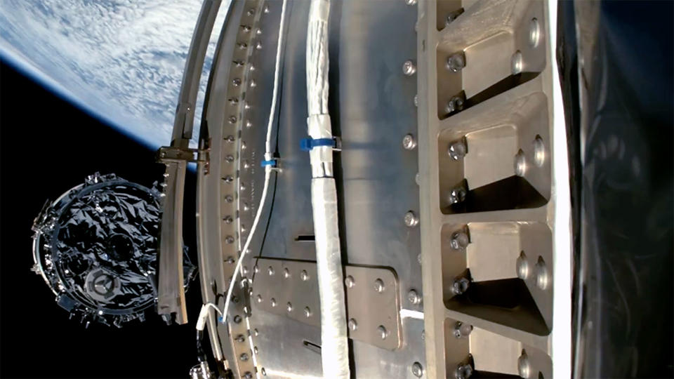 photo of a cylindrical spacecraft being launched from its orbiting rocket, with Earth in the background