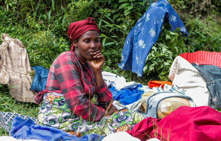 A refugee from the Democratic Republic of Congo sits with her belongings near the United Nations High Commissioner for Refugees (UNHCR) offices in Kiziba refugee camp in Karongi District, Rwanda February 21, 2018. REUTERS/Jean Bizimana