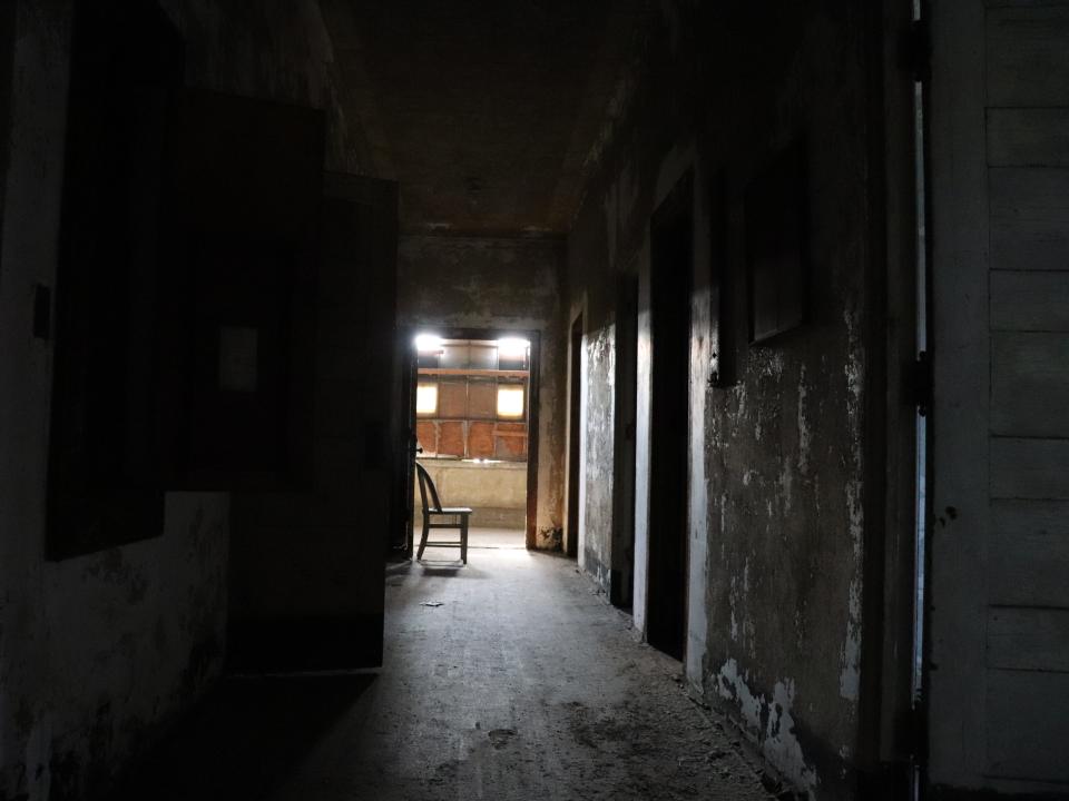 a long dark hallway with a chair at the end at the ellis island hospital