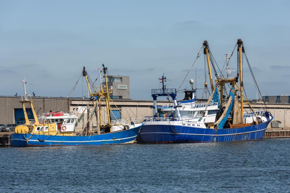 Two fishing boats docked next to a warehouse.