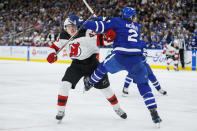 New Jersey Devils defenseman Luke Hughes (43) and Toronto Maple Leafs defenseman Simon Benoit (2) collide during the third period of an NHL hockey game in Toronto on Tuesday, March 26, 2024. (Cole Burston/The Canadian Press via AP)