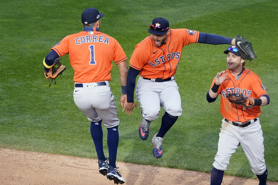 Houston Astros' Carlos Correa, left, and George Springer, center, jump in celebration of the Astros 4-1 win over the Minnesota Twins 4-1 in Game 1 of an American League wild-card baseball series, Tuesday Sept. 29, 2020, in Minneapolis. At right is Josh Reddick. (AP Photo/Jim Mone)