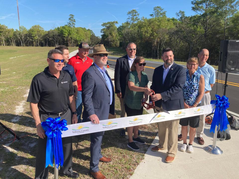 Officials and residents gather in DeLand near State Road 472 to cut a ribbon celebrating the extension of Blue Lake Avenue. From left are Michael Mohler, senior project manager for Consor Engineers; Wallace Combs, project manager with P&S Paving; Michael Hickox, job superintendent with P&S Paving; Michael Pleus, DeLand city manager, County Engineer Tadd Kasbeer, Victoria Park HOA President Connie Tollakson, DeLand Mayor Chris Cloudman, and Victoria Hills residents Diane and Jack Smith.