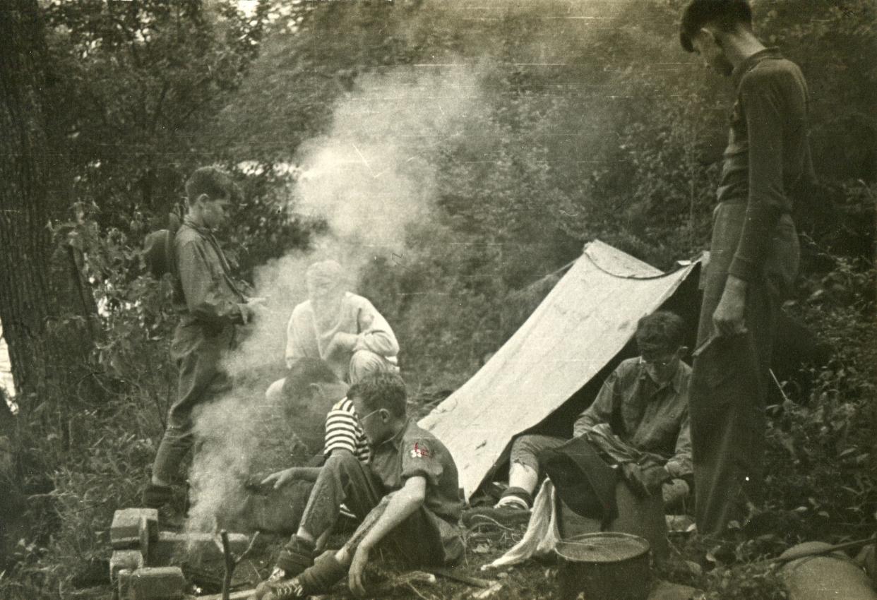 Boy Scout Troop 33 members tend a smoky fire as they gather around a pup tent at a campsite at Camp Red Wing in this photograph from 1939.