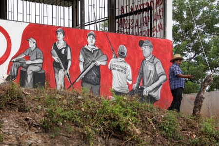 A member of the Community Police is seen next to mural at a checkpoint in the municipality of San Diego Xayakalan