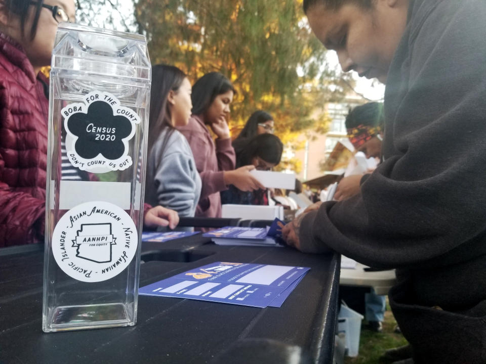 In this Jan. 3, 2020, photo, a woman fills out a pledge card for the U.S. Census in exchange for a reusable boba tea carton at a boba drink competition in Phoenix. The coronavirus has waylaid efforts to get as many people as possible to take part in the census. (AP Photo/Terry Tang)