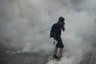 An anti-government protester walks through tear gas smoke during a clash with police at the Wong Tai Sin area in Hong Kong, Tuesday, Oct. 1, 2019. Thousands of black-clad pro-democracy protesters defied a police ban and marched in central Hong Kong on Tuesday, urging China's Communist Party to "return power to the people" as the party celebrated its 70th year of rule. (AP Photo/Felipe Dana )