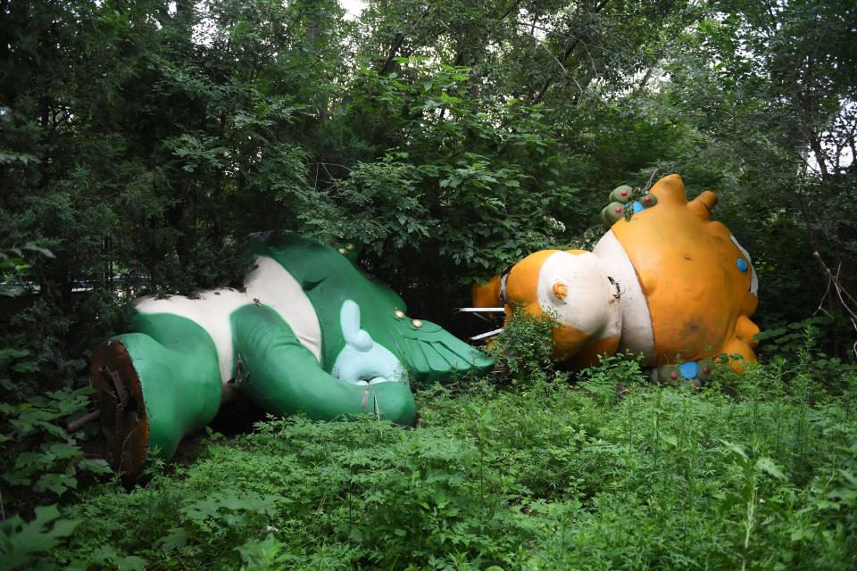 TOPSHOT - This photo taken on July 20, 2018 shows Nini (L) and Yingying, two of the five mascots for the 2008 Beijing Olympic Games, lying among trees behind an abandoned, never-completed mall in Beijing. - A decade after Beijing hosted the 2008 Olympics, its legacy remains unmistakable from the smallest alleyways in the Chinese capital to the country's growing clout abroad. For better or worse, the Games changed the face of Beijing: from the iconic Bird's Nest stadium to the countless blocks of ancient homes bulldozed in an Olympic building frenzy. (Photo by GREG BAKER / AFP) / TO GO WITH China-politics-Olympics-anniversary,FOCUS by Ben Dooley        (Photo credit should read GREG BAKER/AFP via Getty Images)