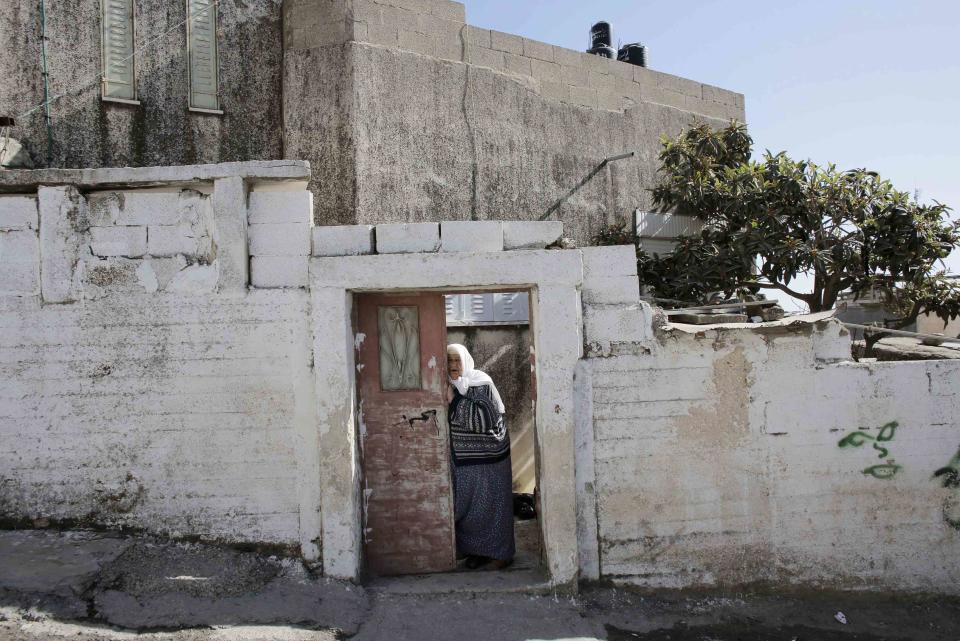 A Palestinian woman stands at the entrance to her house in the Shuafat refugee camp in the West Bank near Jerusalem