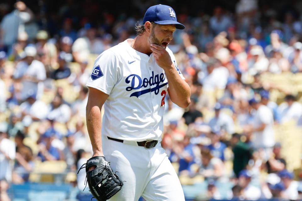 El abridor de los Dodgers Clayton Kershaw se frota la barbilla en el montículo durante un juego en casa
