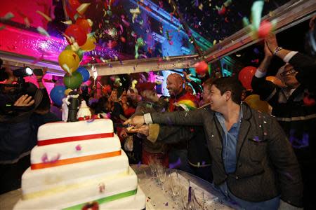 People cut a symbolic wedding cake after parliamentarians voted to recognise same-sex partnerships in the square outside parliament in Valletta April 14, 2014. REUTERS/Darrin Zammit Lupi