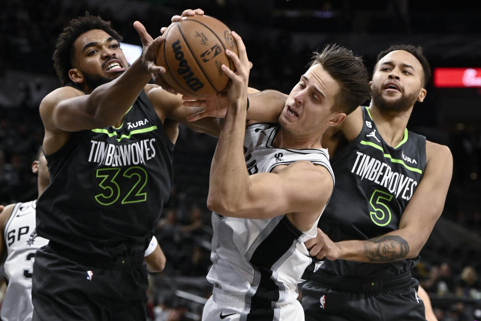 San Antonio Spurs' Zach Collins, center, tangles with Minnesota Timberwolves' Karl-Anthony Towns (32) and Kyle Anderson during the first half of an NBA basketball game, Sunday, Oct. 30, 2022, in San Antonio. (AP Photo/Darren Abate)