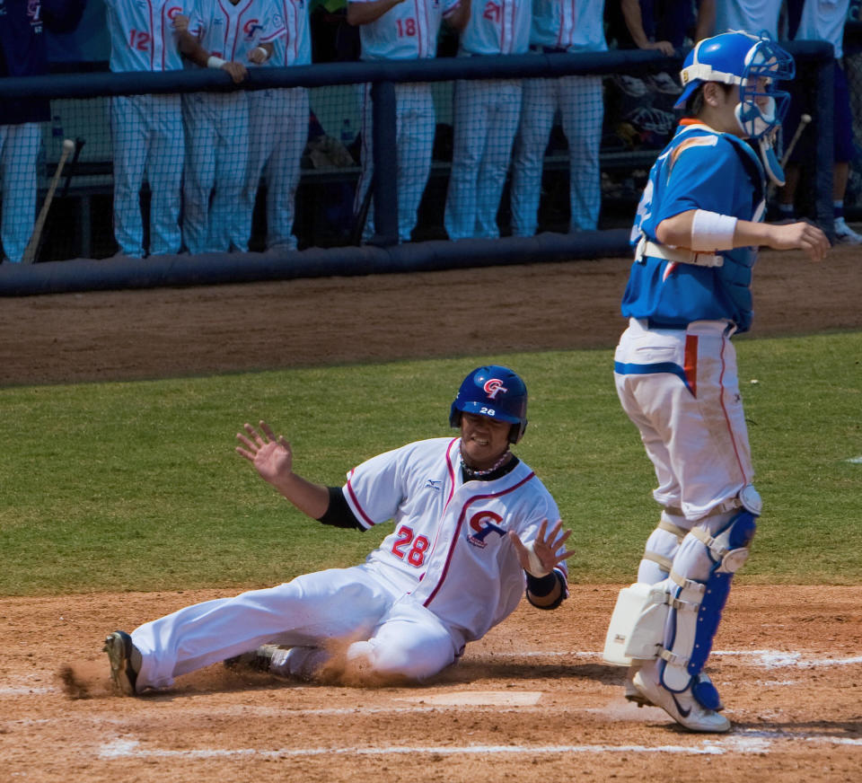 Taiwan leftfielder Lo Kuo-Hui slides into home in front of South Korea's catcher Jin Kabyong (R) scoring the eighth run for his team in the bottom of the sixth inning in their preliminary round baseball game at the Wukesong Baseball Venue during the 2008 Beijing Olympic Games on August 18, 2008.   AFP PHOTO/Omar TORRES (Photo credit should read OMAR TORRES/AFP via Getty Images)