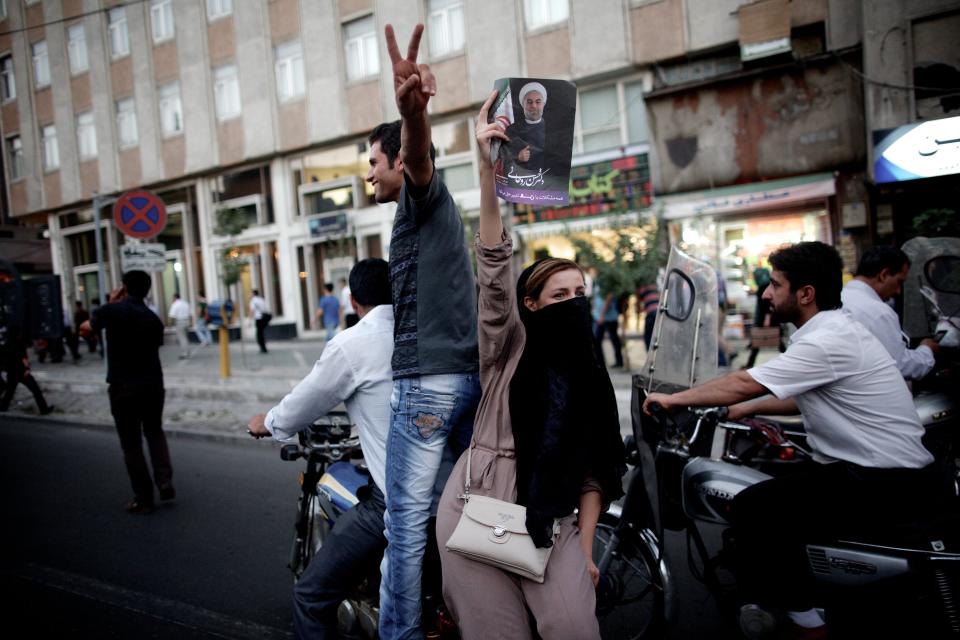 An Iranian woman holds a portrait of moderate presidential candidate Hassan Rouhani as she rides on a motorcycle along Valiasr street in Tehran on June 15, 2013 after he was elected as president. (BEHROUZ MEHRI/AFP/Getty Images)