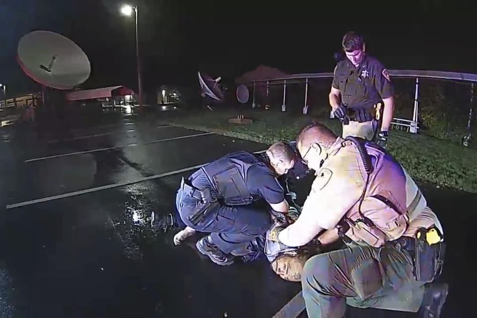 In this image from Altoona Police Department body-camera video, police restrain Demetrio Jackson in a parking lot on the border of Altoona and Eau Claire, Wis., on Oct. 8, 2021, minutes before a paramedic injects him with ketamine. Five medical experts who reviewed the case for AP said Jackson’s behavior did not appear to be dangerous enough to justify the use of ketamine. (Altoona Police Department via AP)