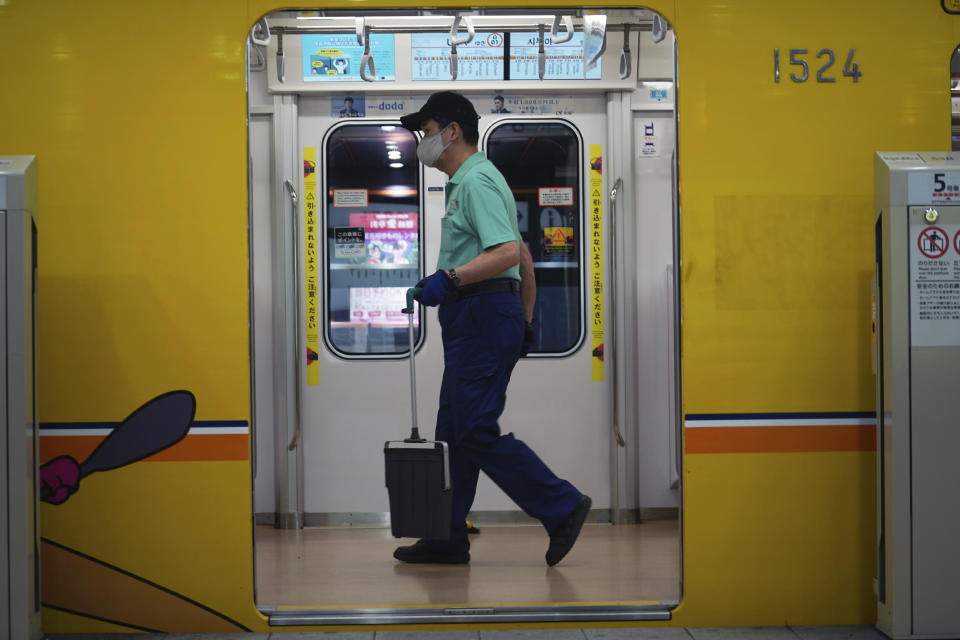 An employee wearing a protective mask to help curb the spread of the coronavirus cleans a subway car Tuesday, Nov. 24, 2020, in Tokyo. The Japanese capital confirmed more than 180 new coronavirus cases on Tuesday. (AP Photo/Eugene Hoshiko)