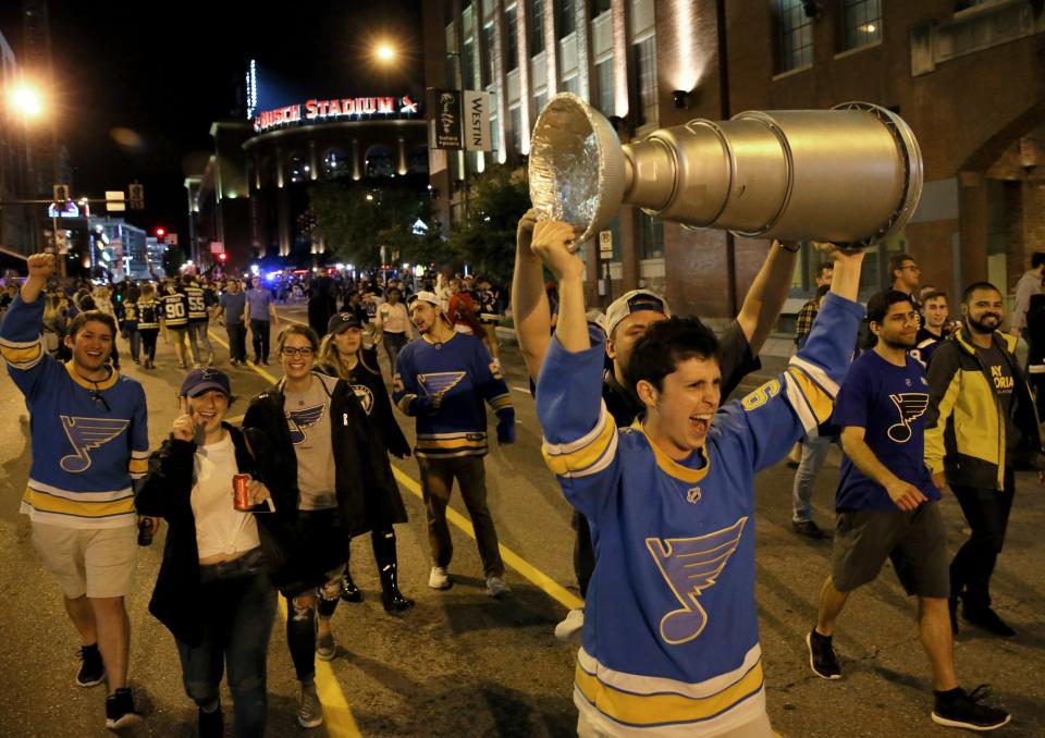 Joel Glasscock, from Belleville, Ill., marches down a St. Louis street Wednesday night, June 12, 2019, with a model of the Stanley Cup he made, after the Blues defeated the Boston Bruins in Game 7 of the NHL hockey Stanley Cup Final in Boston. "I made it a month ago. I had a feeling this year was different," said Glasscock about his homemade Cup. (David Carson/St. Louis Post-Dispatch via AP)