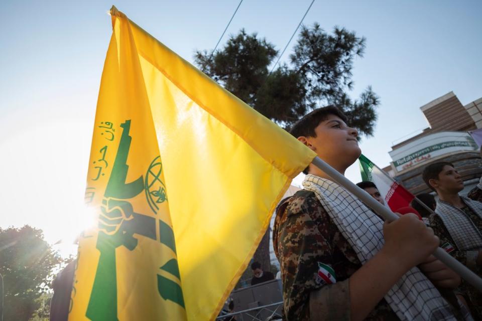 An Iranian schoolboy who wears a military uniform of Islamic Revolutionary Guard Corps holds a Hezbollah flag while waiting to perform in an anti-Israel protest in downtown Tehran on August 9, 2022. (Photo by Morteza Nikoubazl/NurPhoto via Getty Images)