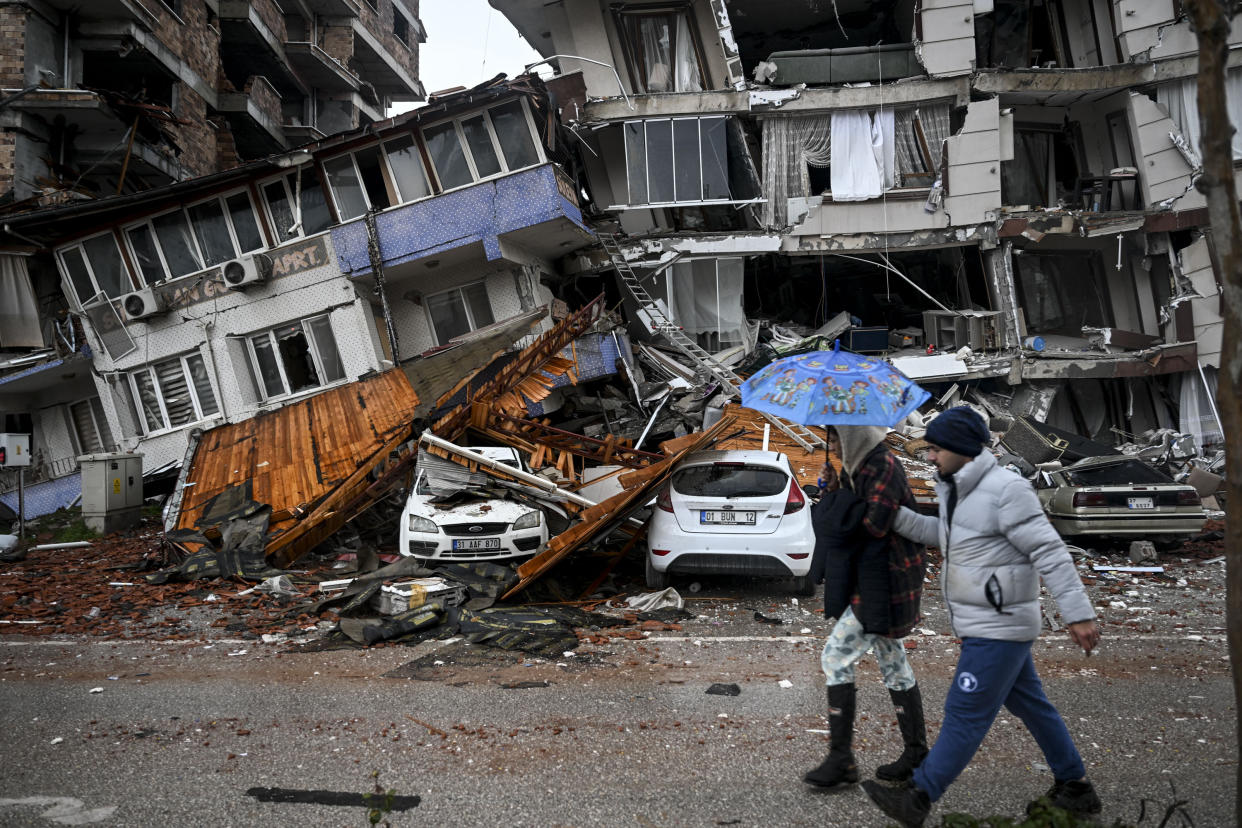 A couple walk by a damaged building in Hatay Province, Turkey.